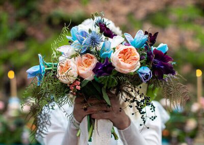 Novia sosteniendo un ramo de flores de colores en una boda de otoño en el bosque