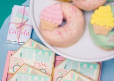 Donuts decorados con helados y cupcakes junto a galletas personalizadas con el nombre Carlota en una fiesta infantil